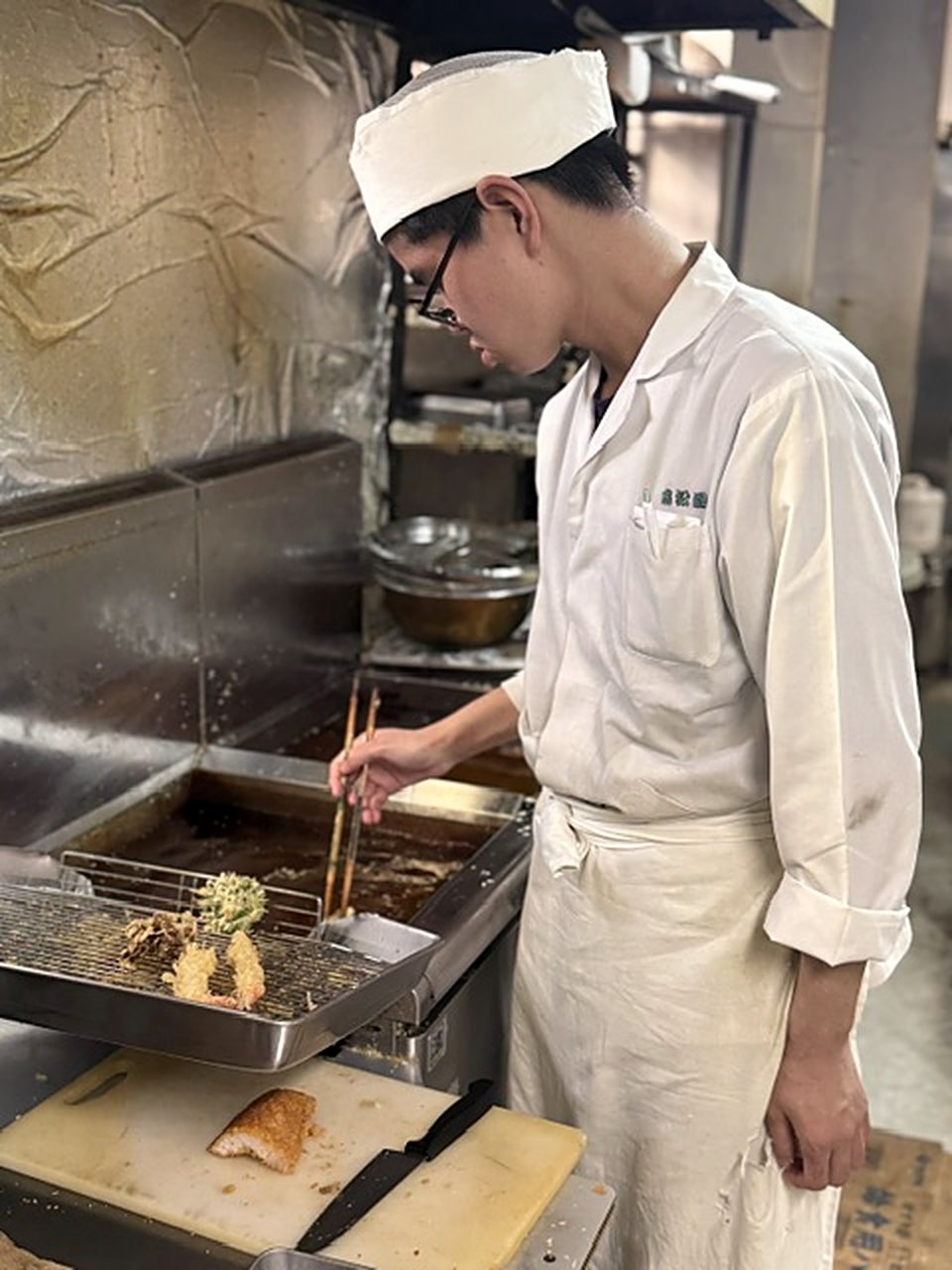 厨房で揚げ物を仕上げる料理人